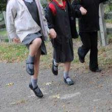 Three school pupils skipping along a path