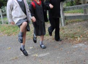 Three school pupils skipping along a path